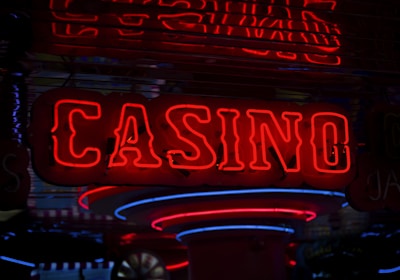Neon lights display the word 'CASINO' in bright red, standing out against a dark background. The vibrant glow reflects a lively and bustling atmosphere.